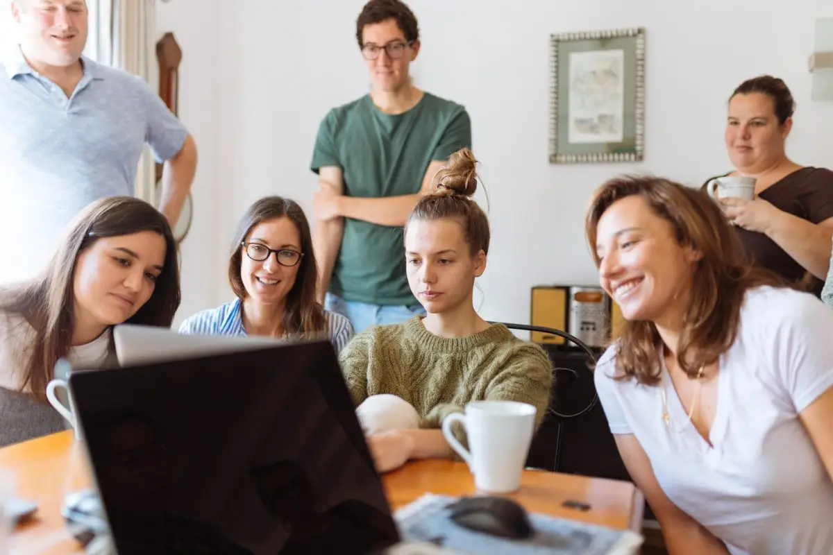 8 adults gathered around a computer