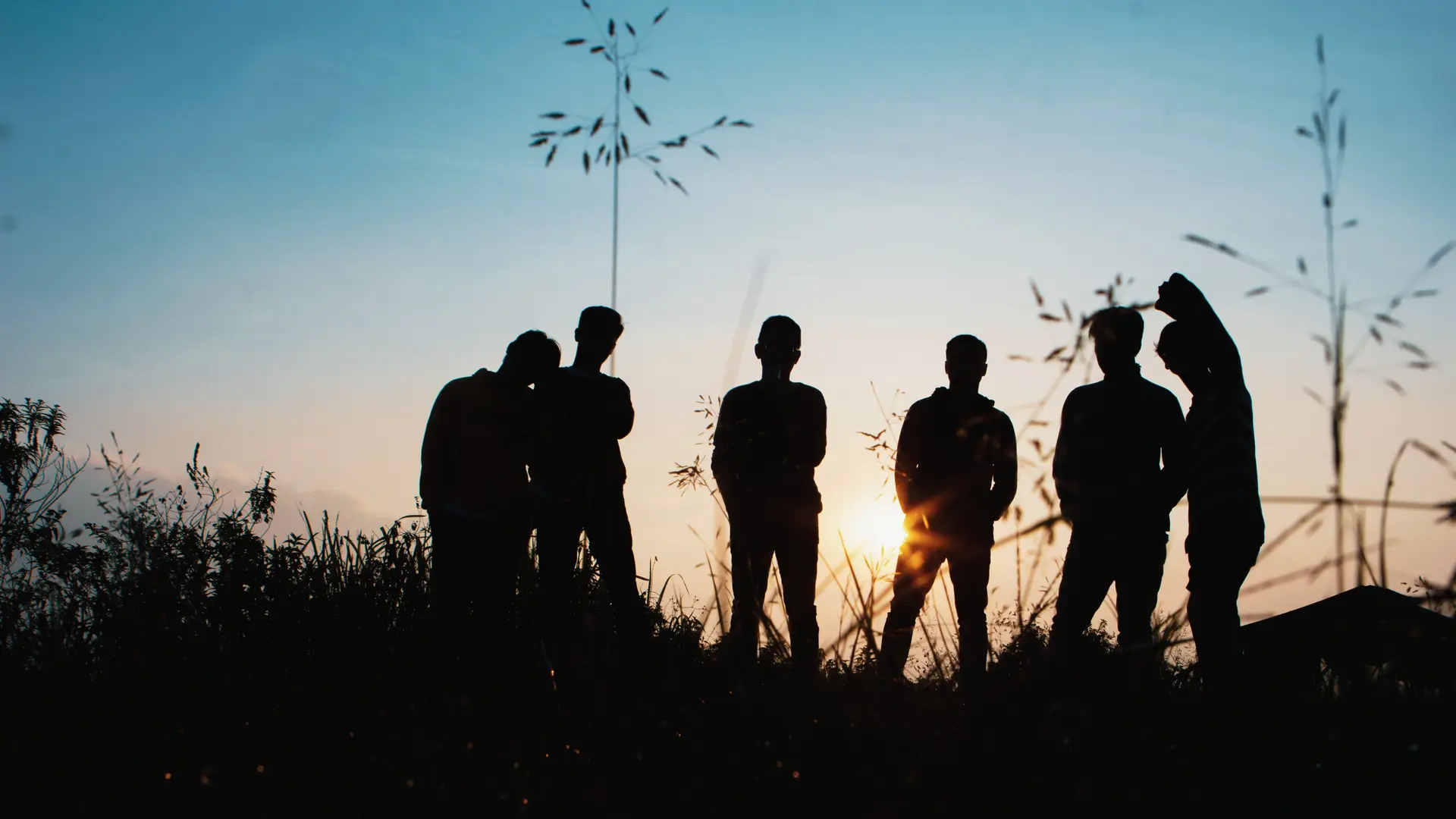 A group of boys standing watching the sunset