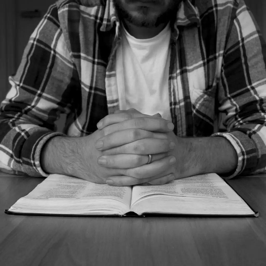 Hands folded in prayer over Bible