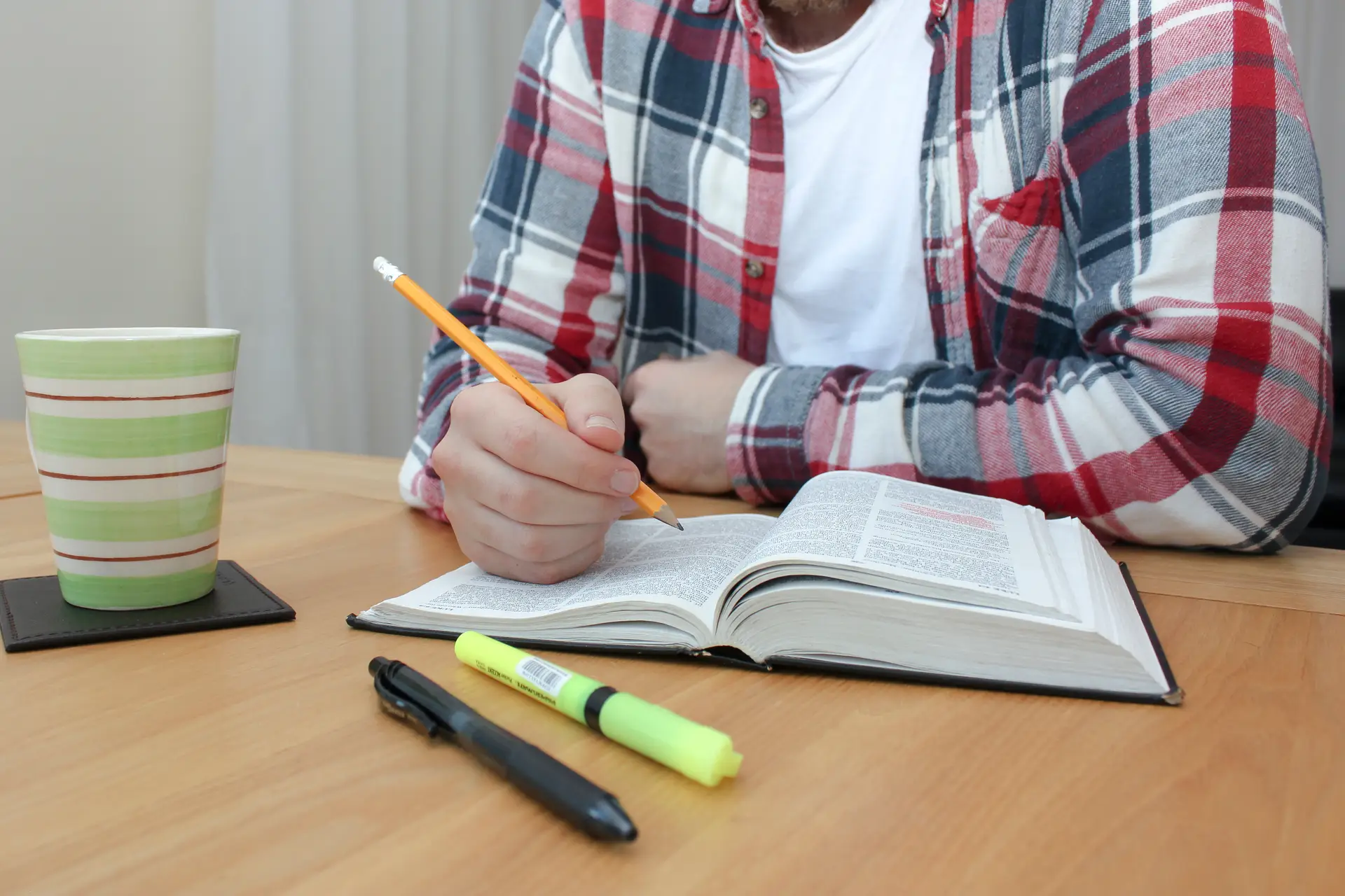 Bible, pens, and pencils with man studying