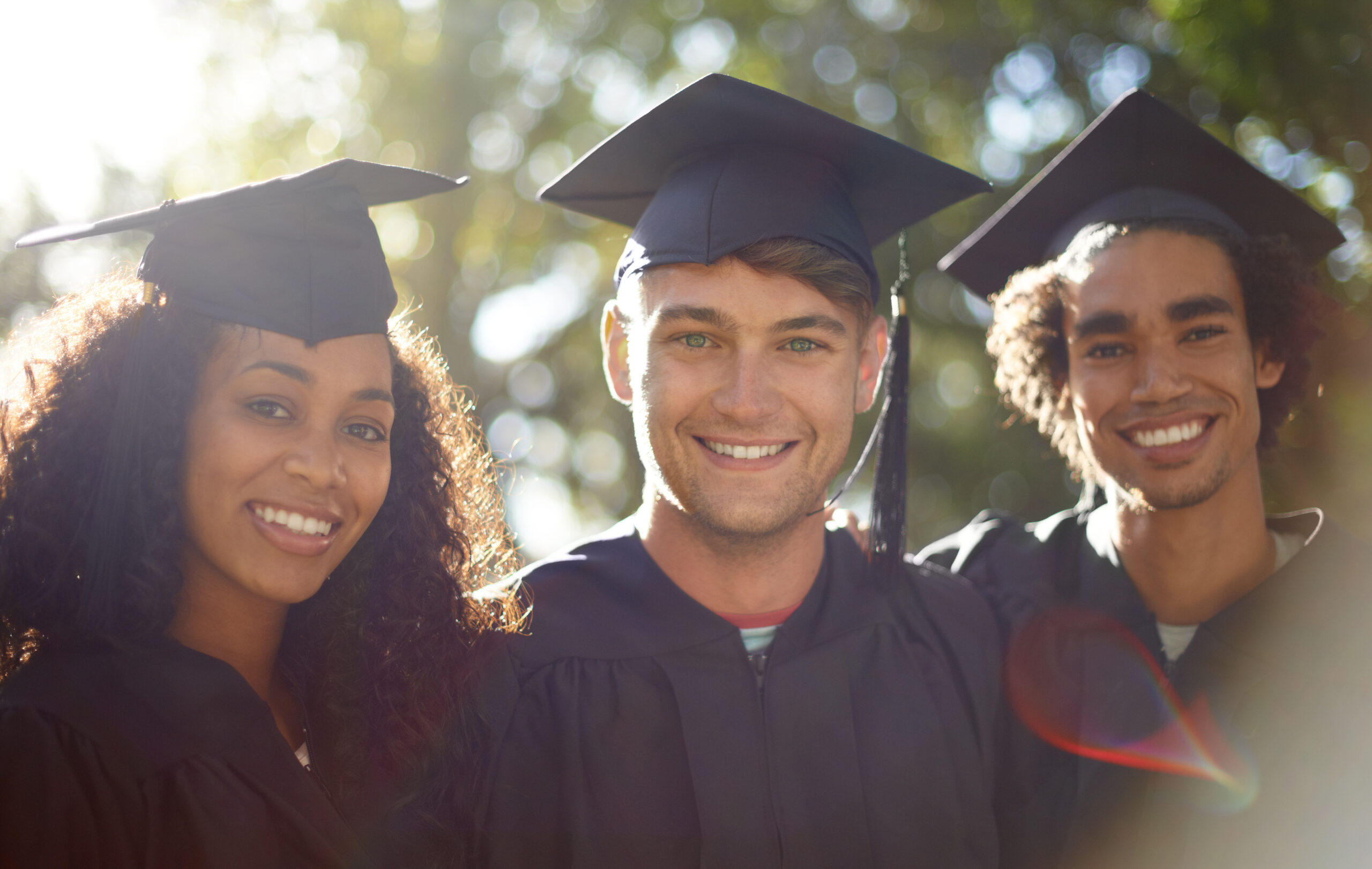 Portrait of three happy students on graduation day.