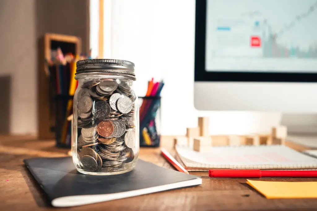 Money in a glass jar on a desk in a home