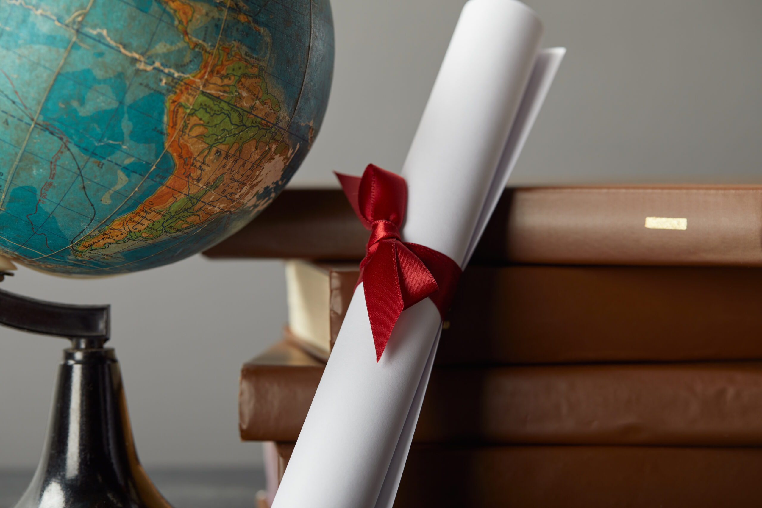 Brown books, globe and diploma with red ribbon