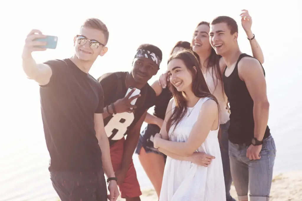 Happy friends pose for selfie on the beach