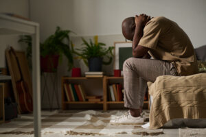 Young man sitting on a bed worried about his problems.