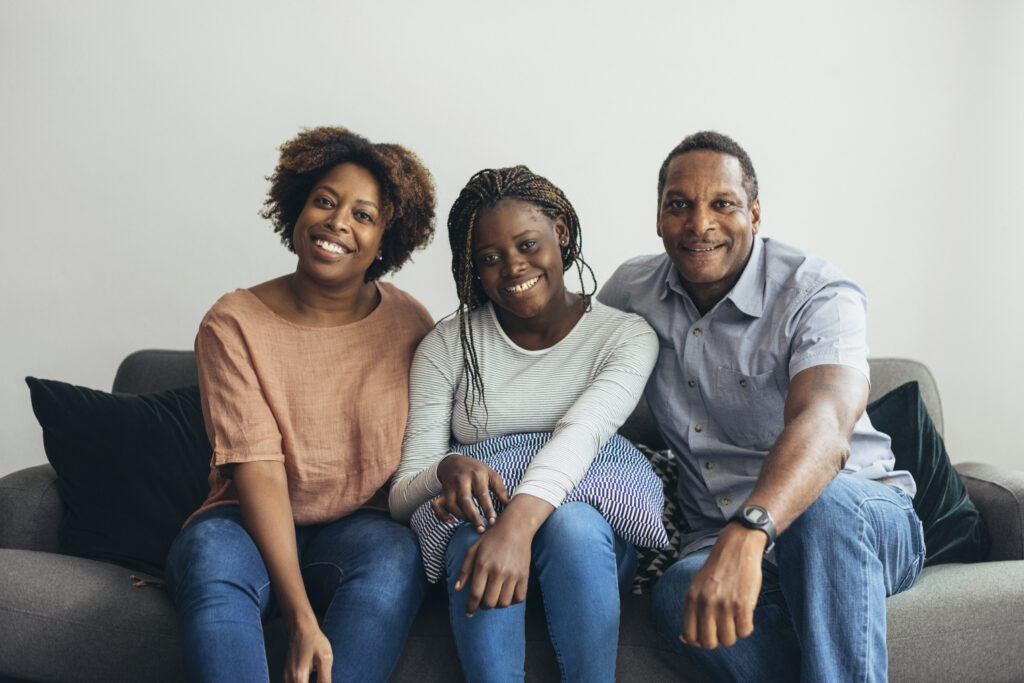 Parents and daughter sitting on a gray couch.