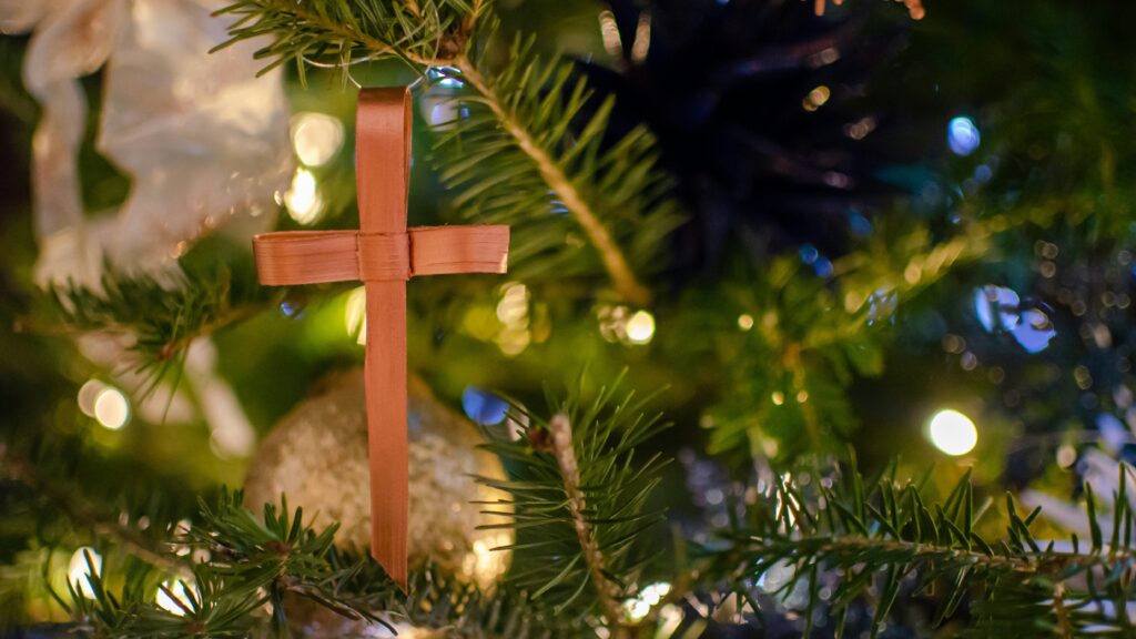 Brown cross ornament on a green Christmas tree