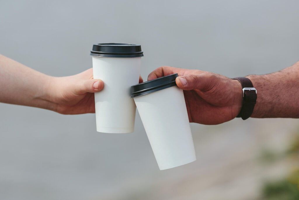 Two men cheers disposable coffee cups